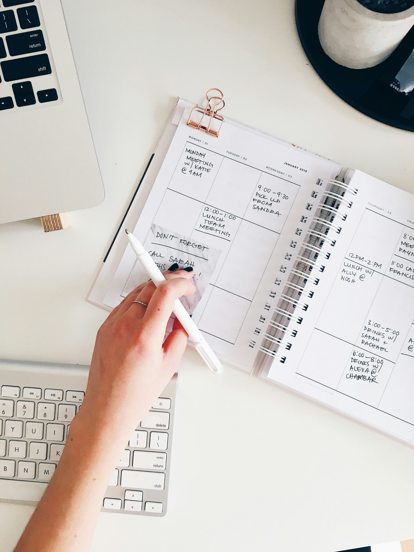 A weekly planner open on a desk beside a laptop