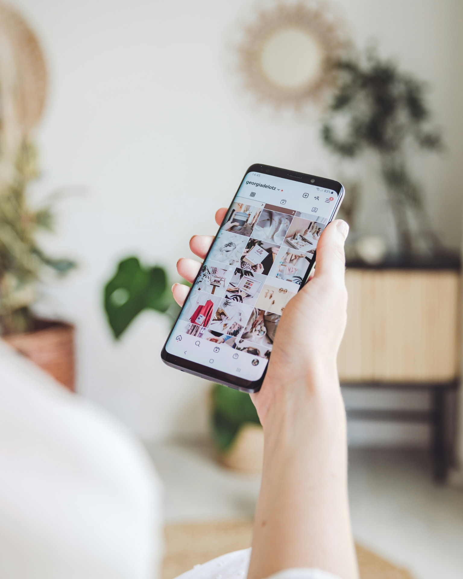 A beauty client scrolling an Instagram profile grid on her phone
